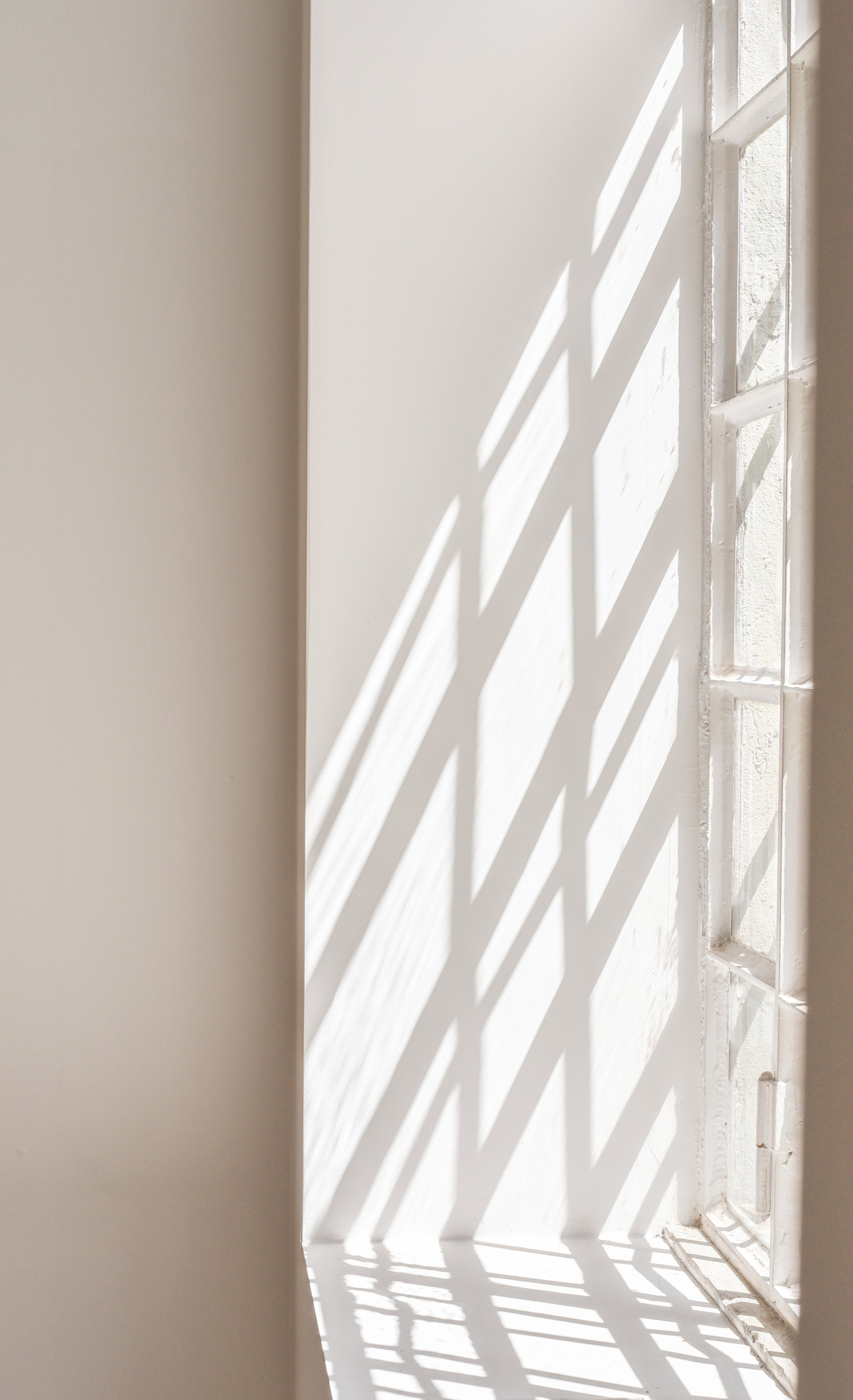 Sunlight coming through a window creating striped shadow patterns on a wall
